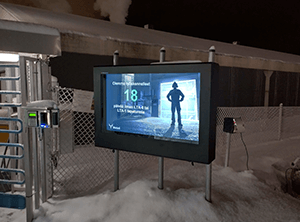 A 55" outdoor digital signage enclosure installed before a ski-lift in a snowy environment